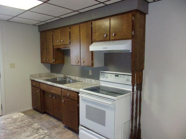 kitchen with electric stove, light tile floors, a paneled ceiling, and sink