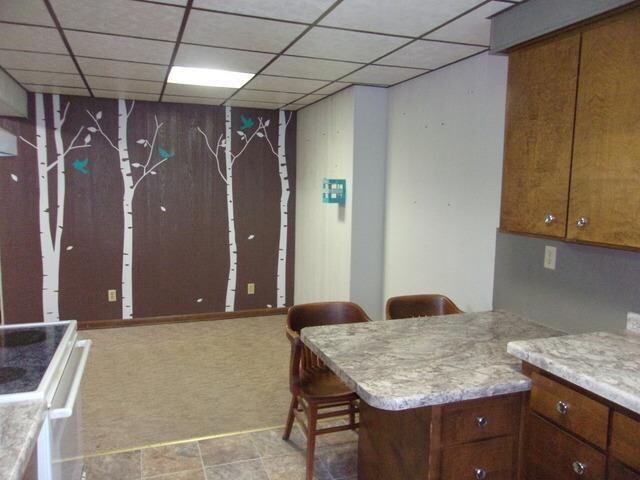 kitchen with a kitchen bar, light tile floors, a drop ceiling, and white range oven