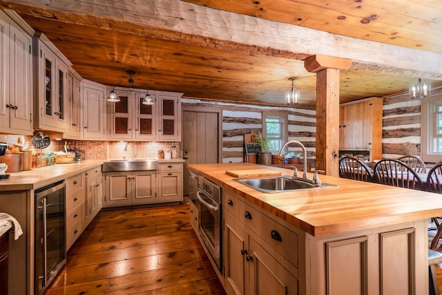 kitchen featuring dark wood-type flooring, hanging light fixtures, wine cooler, wood counters, and sink