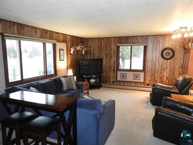 19020 US Highway 2, Mason, WI 54856 - living room with wooden walls, light carpet, and a baseboard heating unit