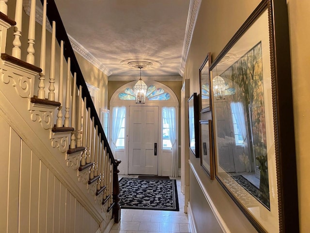 tiled entrance foyer featuring an inviting chandelier and crown molding