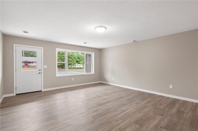 spare room featuring a textured ceiling and light hardwood / wood-style flooring