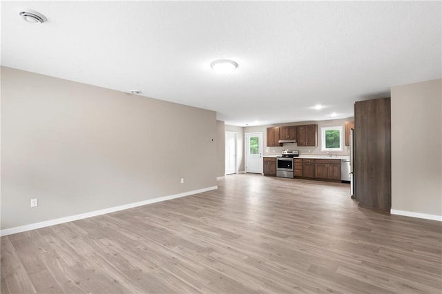 unfurnished living room featuring light wood-type flooring and sink