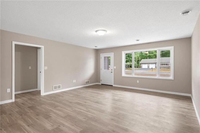 spare room featuring light wood-type flooring and a textured ceiling