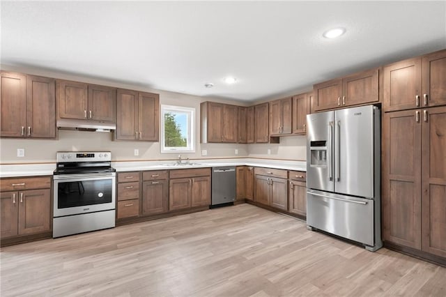 kitchen with appliances with stainless steel finishes, sink, and light hardwood / wood-style floors