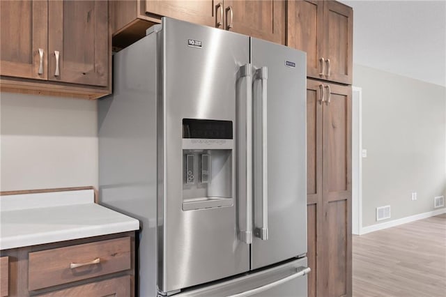 kitchen with stainless steel refrigerator with ice dispenser and light hardwood / wood-style floors