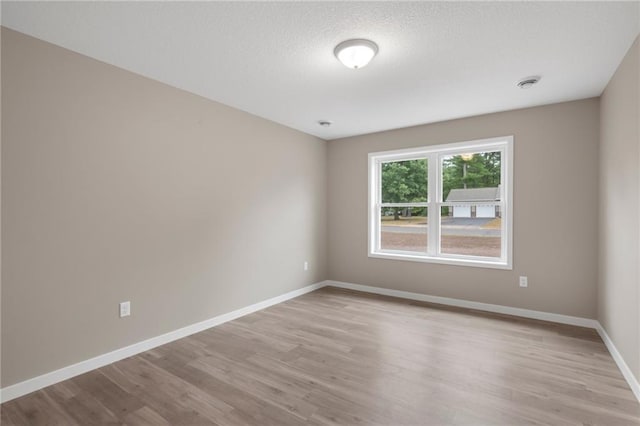 empty room with a textured ceiling and light wood-type flooring