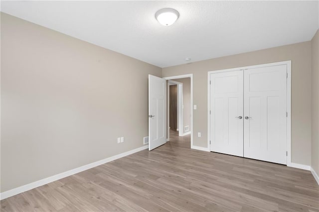 unfurnished bedroom featuring a closet and light hardwood / wood-style floors