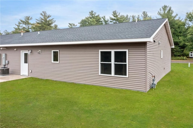 back of house with central AC unit, a lawn, and a patio area