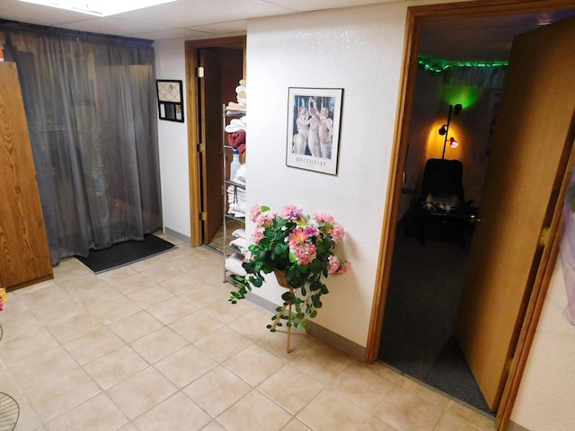 hallway with a drop ceiling and light tile floors