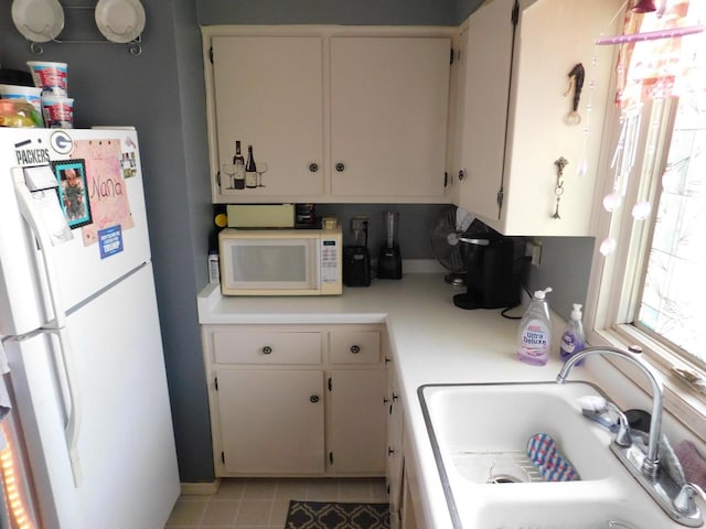 kitchen with white appliances, sink, and light tile flooring