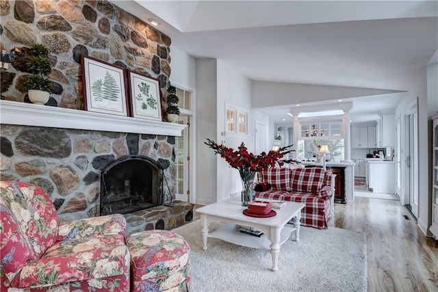 living room featuring a fireplace, light wood-type flooring, and vaulted ceiling