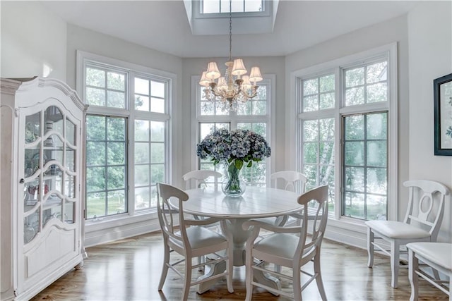 dining space with a healthy amount of sunlight, light hardwood / wood-style floors, and an inviting chandelier