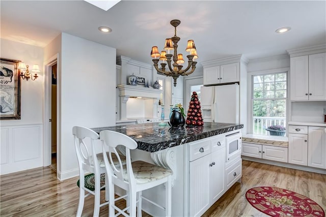 kitchen with pendant lighting, a notable chandelier, light hardwood / wood-style flooring, white appliances, and white cabinets