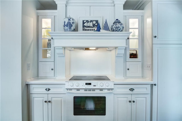 kitchen with white cabinetry, custom range hood, crown molding, and white range with electric stovetop