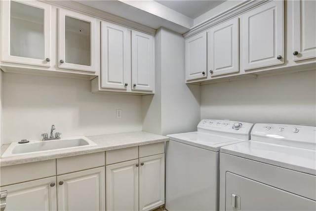 laundry room with cabinets, washer and dryer, and sink