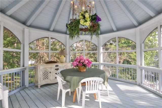 sunroom featuring an inviting chandelier and lofted ceiling with beams