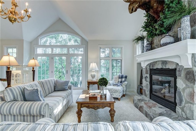 living room with a notable chandelier, a healthy amount of sunlight, light carpet, and a stone fireplace