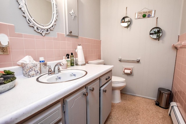 bathroom with a baseboard radiator, toilet, vanity with extensive cabinet space, backsplash, and tile walls