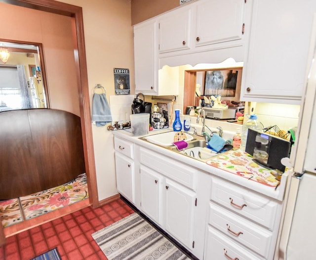 kitchen featuring white cabinetry, dark tile flooring, and sink