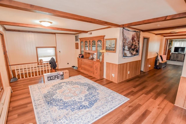 interior space featuring beam ceiling, wood-type flooring, and a baseboard heating unit