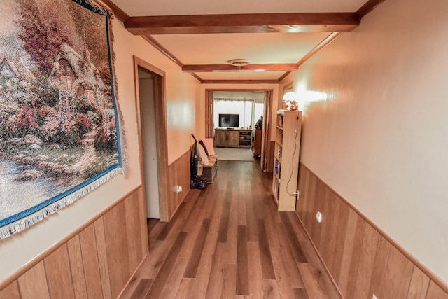 corridor with beam ceiling and light hardwood / wood-style flooring