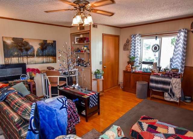 living room featuring ceiling fan, light wood-type flooring, and a textured ceiling