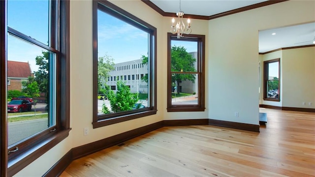 spare room featuring light hardwood / wood-style flooring, a chandelier, and a healthy amount of sunlight