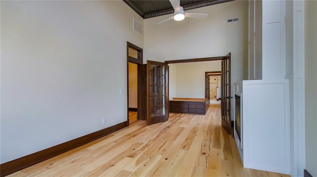 hall featuring a towering ceiling and light hardwood / wood-style flooring