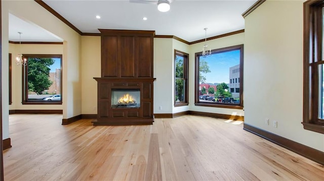 unfurnished living room with light hardwood / wood-style flooring, ornamental molding, and ceiling fan with notable chandelier