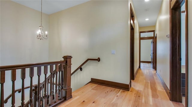 hallway with an inviting chandelier and light hardwood / wood-style floors