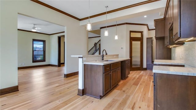 kitchen featuring hanging light fixtures, an island with sink, ceiling fan, light hardwood / wood-style floors, and sink