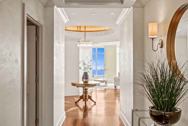 corridor with an inviting chandelier, light wood-type flooring, and crown molding