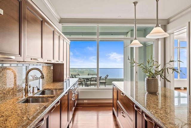 kitchen with dark wood-type flooring, a wealth of natural light, light stone counters, tasteful backsplash, and pendant lighting