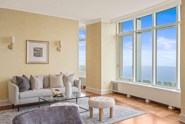 living room with crown molding, a water view, a healthy amount of sunlight, and light parquet floors