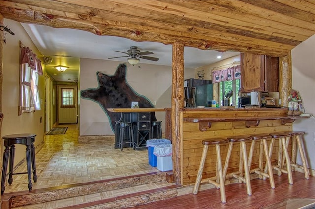 bar with light parquet floors, black refrigerator, and ceiling fan