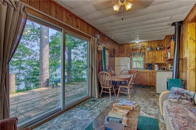 sunroom / solarium featuring ceiling fan and a wood stove