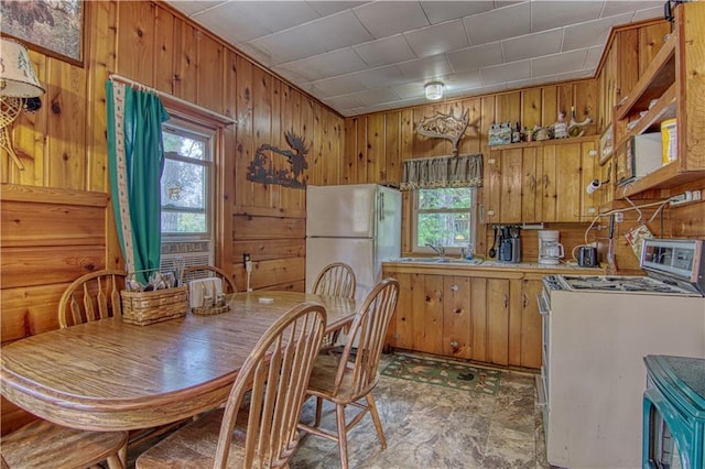 tiled dining area featuring sink, wood walls, and a wealth of natural light