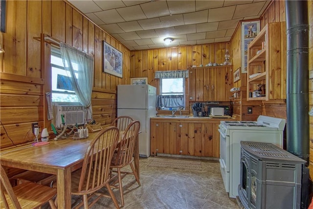 kitchen featuring wooden walls, a wood stove, and white refrigerator