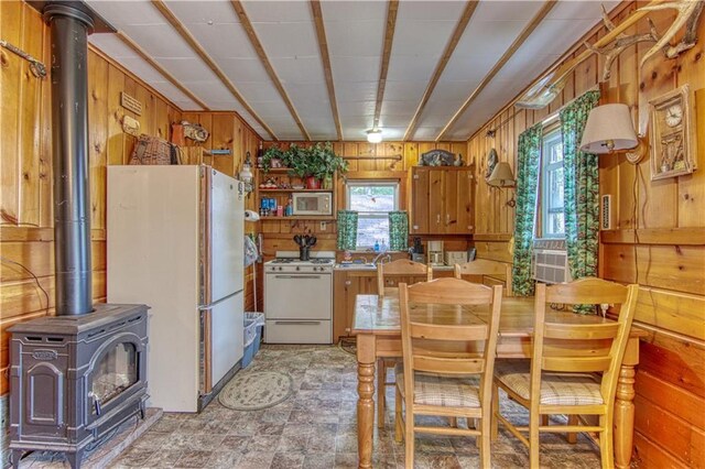 kitchen with light tile floors, white appliances, a wood stove, and a wealth of natural light