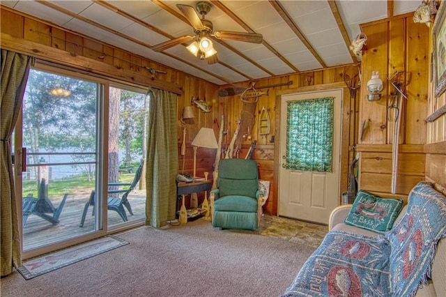 unfurnished room with wood walls, ceiling fan, and light colored carpet