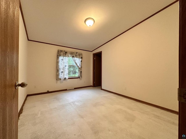 carpeted spare room featuring crown molding and vaulted ceiling