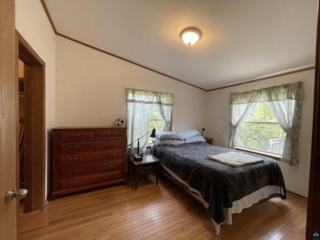 bedroom with crown molding, light hardwood / wood-style floors, and lofted ceiling