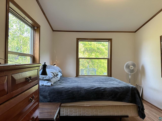 bedroom with crown molding, hardwood / wood-style floors, and multiple windows