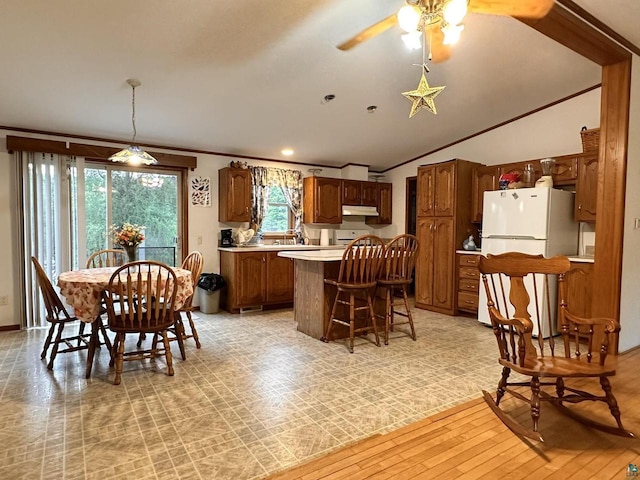 dining area with ornamental molding, vaulted ceiling, ceiling fan, and light wood-type flooring