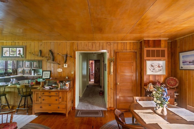 dining area with wooden walls, wooden ceiling, and dark colored carpet