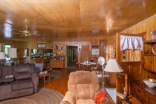 living room with ceiling fan, dark hardwood / wood-style floors, and wooden walls