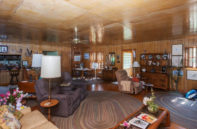 living room with wooden walls, ceiling fan, and a healthy amount of sunlight