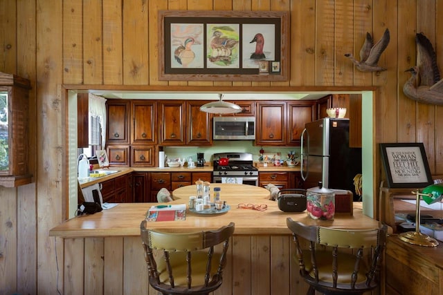 kitchen with appliances with stainless steel finishes, sink, wooden counters, and wood walls