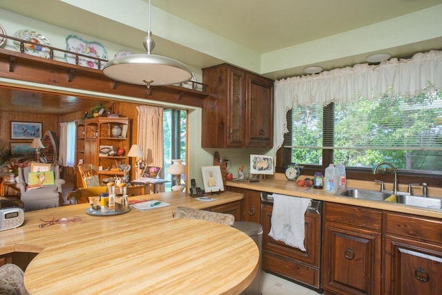 kitchen with wooden walls, decorative light fixtures, and sink